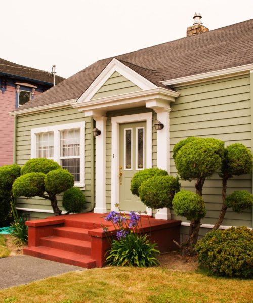 a small house with green siding and white trim